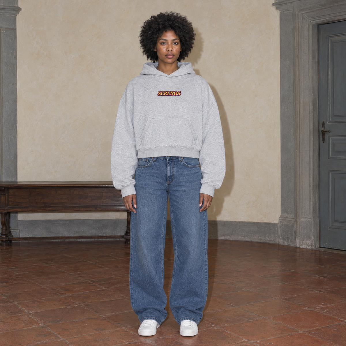 Woman wearing the SERENOS Success oversized boxy hoodie in flower gray, front view with the centred SERENOS chest logo, cropped boxy fit
