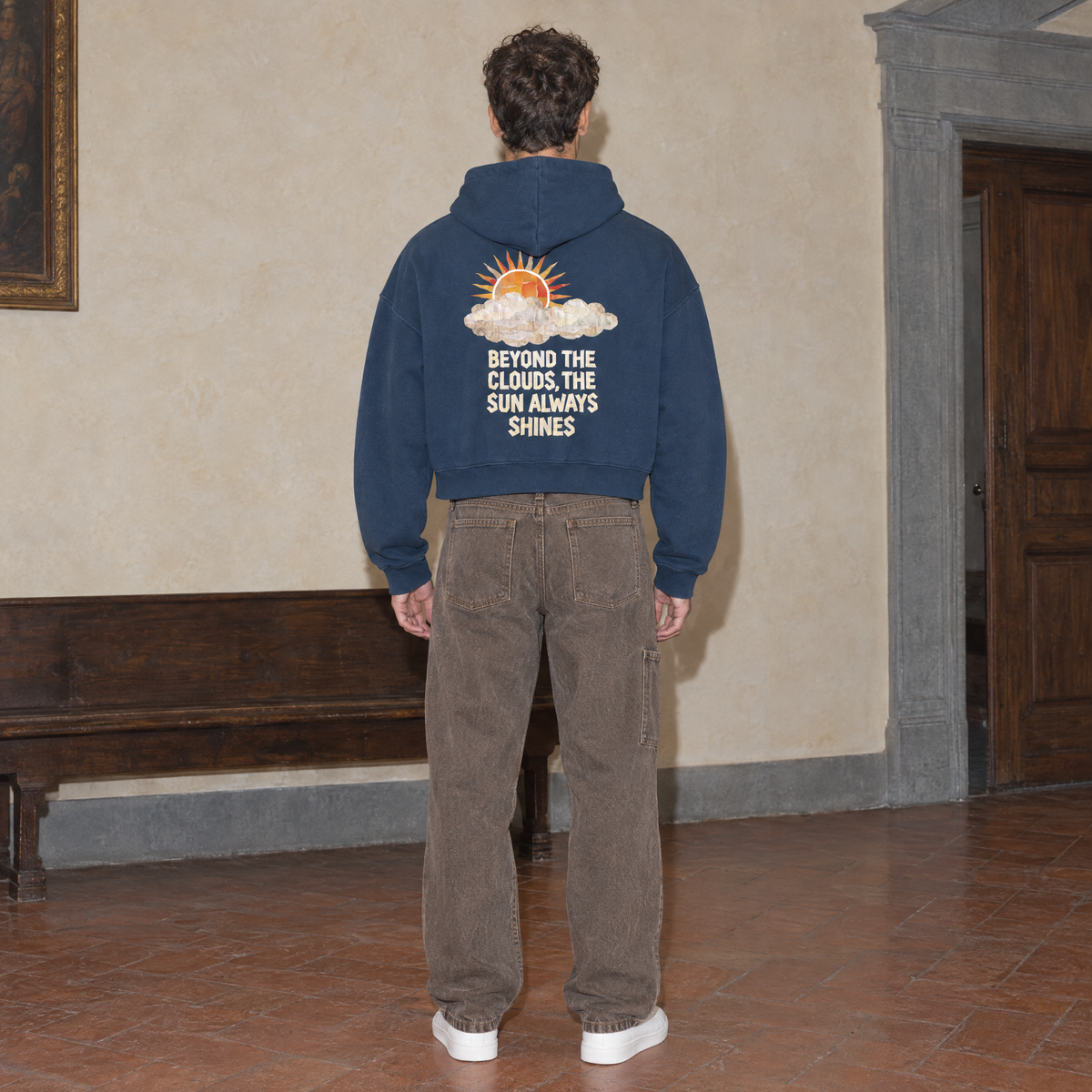 Man seen from behind wearing the navy SERENOS Sun Above oversized boxy hoodie with the Beyond The Clouds The Sun Always Shines back print, cropped boxy fit