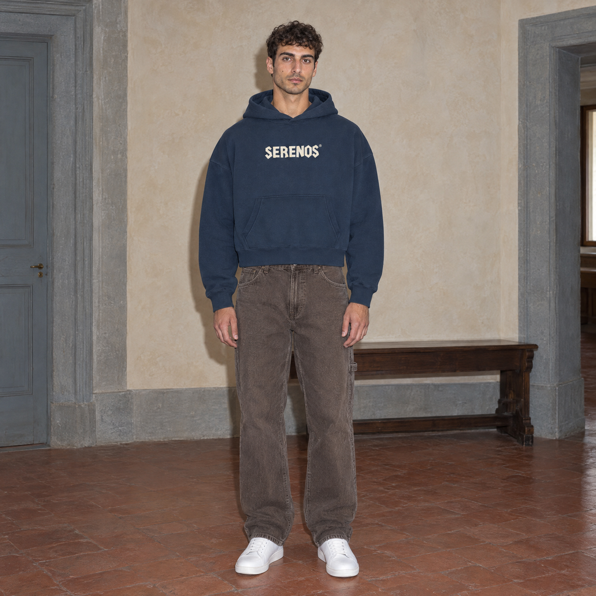 Man wearing the navy SERENOS Sun Above oversized boxy hoodie, front view with the cream Serenos chest wordmark, cropped boxy fit