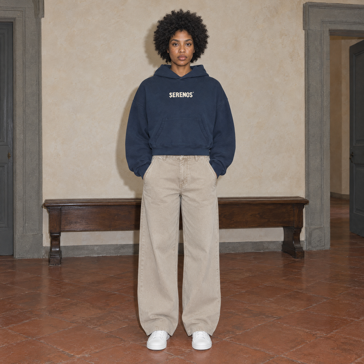 Woman wearing the navy SERENOS Sun Above oversized boxy hoodie, front view with the cream Serenos chest wordmark, cropped boxy fit
