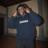 Lifestyle shot of a man pulling up the hood of the navy SERENOS Sun Above boxy hoodie in a Florentine palazzo