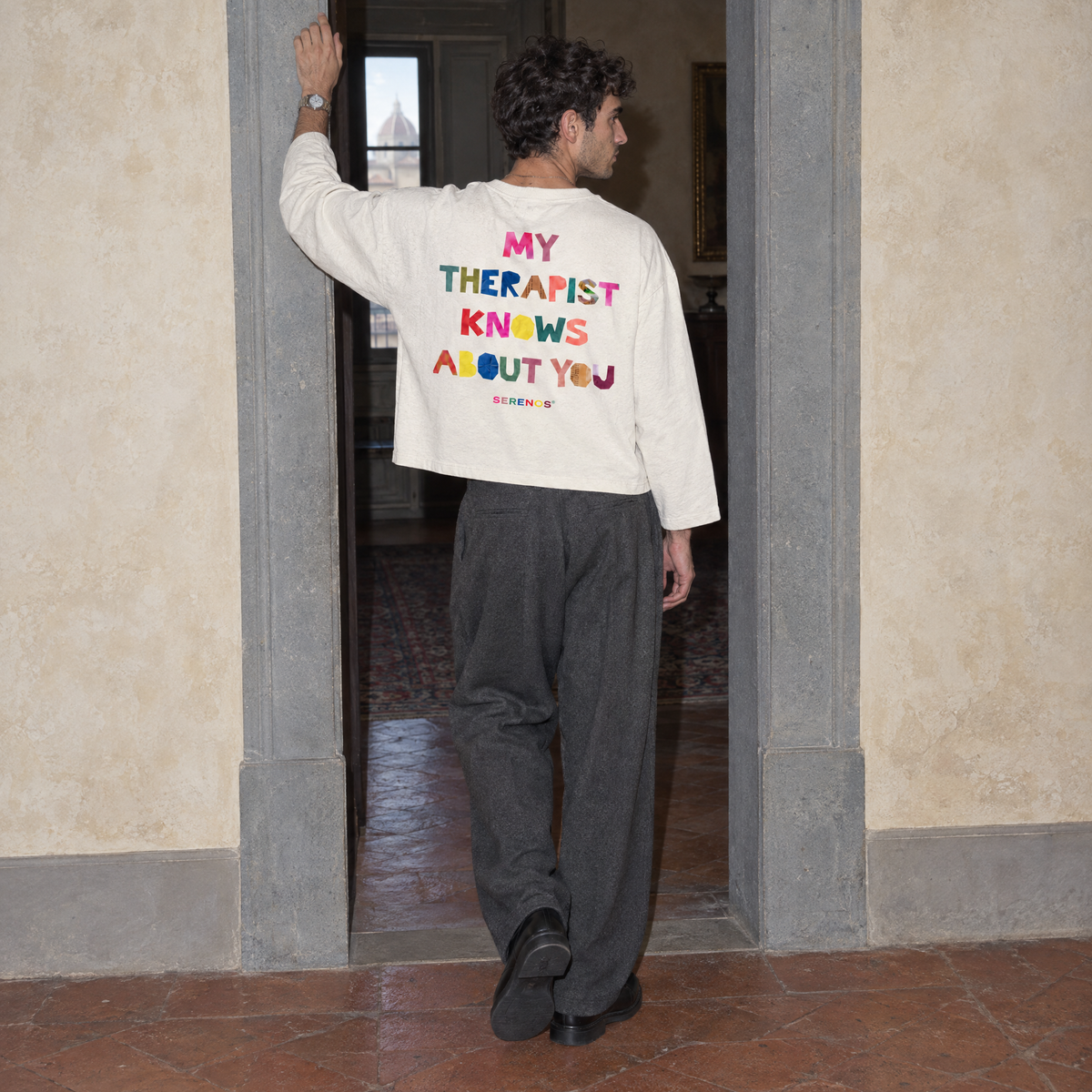 Man seen from behind wearing the cream Therapist long sleeve by Serenos, back print reading my therapist knows about you