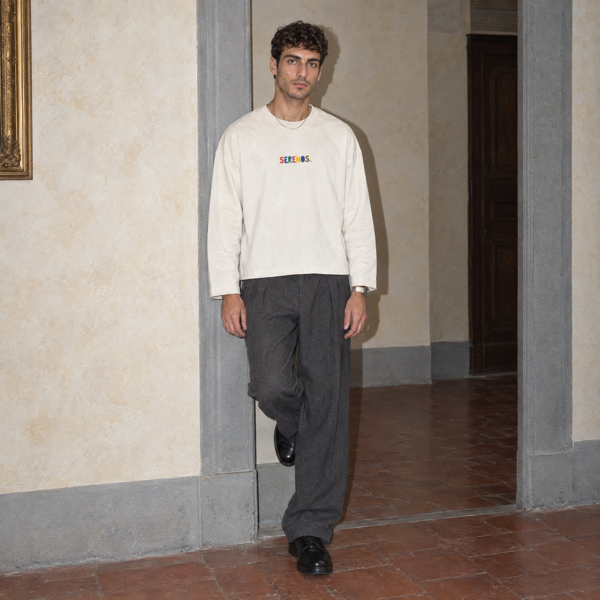 Man wearing the cream Therapist long sleeve by Serenos, front view with the multicoloured Serenos chest logo
