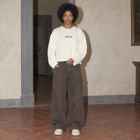 Woman wearing the cream Therapist long sleeve by Serenos, front view with the multicoloured Serenos chest logo