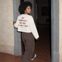 Woman walking through a doorway in a Florentine palazzo wearing the cream Therapist long sleeve by Serenos
