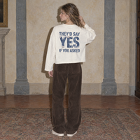 Woman seen from behind wearing the cream Yes long sleeve by Serenos, denim texture back print reading they'd say yes if you asked