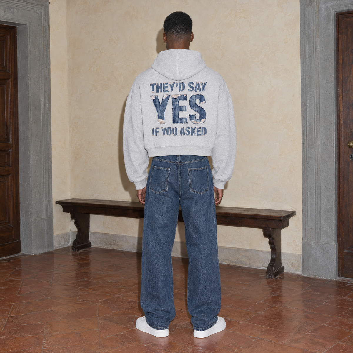 Man wearing the SERENOS Yes oversized boxy hoodie in flower gray, seen from behind showing the They'd Say Yes If You Asked denim back print, cropped boxy fit