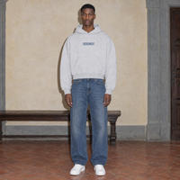 Man wearing the SERENOS Yes oversized boxy hoodie in flower gray, front view with the centred denim SERENOS chest logo, cropped boxy fit