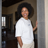 Woman laughing in a stone doorway of a Florentine palazzo wearing the white Yes t-shirt